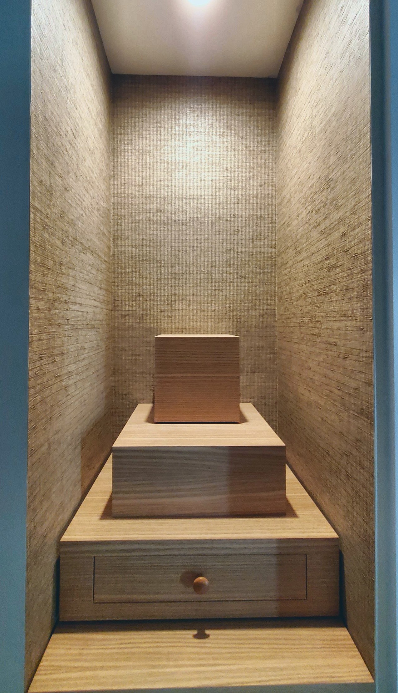 Oak art pedestal in a lit niche